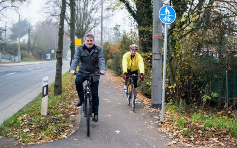 Radfahren auf der Saarstraße nun komfortabler und sicherer Der radfreundliche Umbau der Saarstraße ist abgeschlossen: Zwischen Schierstein und der Erich-Ollenhauer-Straße wurden beidseitig auf einer Strecke von rund 2,3 Kilometer Radverkehrsanlagen eingerichtet. „In den vergangenen zwei Jahren haben wir in Wiesbaden im Rekordtempo viele wichtige Straßen für den Radverkehr fitgemacht. Mit der neuen Verbindung auf der Saarstraße kommen wir der Fertigstellung des Rad-Grundnetzes 2020 ein großes Stück näher“, verkündet Andreas Kowol, Dezernent für Umwelt, Grünflächen und Verkehr. Auch Schiersteins Ortsvorsteher Urban Egert begrüßt die bessere Verbindung: „Radlerinnen und Radler aus Schierstein, aber auch aus dem Rheingau, können jetzt ohne größere Umwege bequem in die Innenstadt fahren. Für Pendlerinnen und Pendler ist diese Strecke, insbesondere auch mit dem E-Bike, sicher eine interessante Option.“ „Auch die Biebricherinnen und Biebricher im nördlichen Teil unseres Ortsbezirks, also in den Siedlungen Sauerland, Gräselberg und um die Waldstraße, profitieren von den neuen Radwegen auf der Saarstraße, da sie nun mit dem Rad sicherer nach Schierstein und an den Rhein kommen“, ergänzt Markus Michel, stellvertretender Ortsvorsteher von Biebrich. Die Arbeiten begannen im November 2019 und wurden bis auf kleinere Restarbeiten kürzlich beendet. Im Bereich von der Stielstraße bis zur Alten Schmelze - mit der Unterführung unter der Bahnlinie - wurde der vorhandene Gehweg grundhaft saniert und zur kombinierten Nutzung für Fußgänger und Radfahrer freigegeben. Im Bereich außerorts zwischen der Überquerung der Autobahn und der Einmündung der Wörther-See-Straße wurde der vorhandene sehr schmale und unebene Geh- und Radweg beidseitig ertüchtigt und, sofern es die Örtlichkeiten zugelassen haben, auf ein komfortables Maß verbreitert. Im Bereich der Auf- und Abfahrten von den kombinierten Geh- und Radwegen auf die Schutzstreifen entlang der Fahrbahn wurden Absenkungen in der Bordsteineinlage sowie teilweise Schutzanlagen/-inseln hergestellt. Der nördliche Abschnitt bis zur Kahlen Mühle wurde als Radstreifen hergestellt; weitere Abschnitte, insbesondere in Schierstein innerorts, als Schutzstreifen. Ein Ampelmast, der derzeit noch mittig auf dem gemeinsamen Geh- und Radweg auf Höhe der Einmündung Alte Schmelze steht, soll versetzt werden. Die Gesamtmaßnahme kommt auch dem Fußverkehr und insbesondere Menschen mit eingeschränkter Mobilität zugute: Wichtiger Bestandteil der Planung war die Verbreiterung des Gehwegs im Bereich der Einmündungen Sylter Straße und Wörther-See-Straße. Somit wurde erstmals ein barrierefreier Zugang zu den Bushaltestellen „Kallebad“ geschaffen. Der gesamte Knotenpunkt wurde umgebaut und die beiden Bushaltestellen wurden in diesem Zuge ebenfalls barrierefrei ausgebaut. In Teilabschnitten der Saarstraße, in denen umfangreiche Anpassungen der Fahrbahnmarkierung für die Herstellung des Radfahrstreifens erforderlich wurden, sowie im Bereich der neu hergestellten Bushaltestellen, wurde zudem die gesamte Fahrbahndecke erneuert. Für den Umbau der Saarstraße wurden Baukosten von etwa. 2,5 Millionen Euro aufgewendet. Die Maßnahme wurde durch den Bund mit Mitteln aus der Verkehrsinfrastrukturförderung nach dem Gemeindeverkehrsfinanzierungsgesetz zur Verbesserung und nachhaltigen Mobilitätsentwicklung gefördert.
