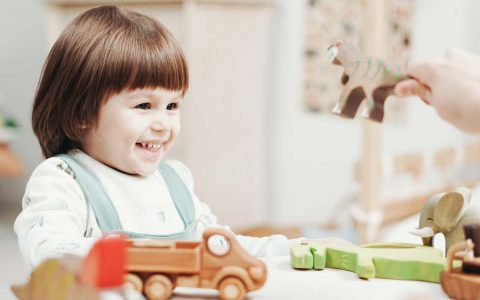 Tagesmüttervermittlung: Kind wird bespielt und lacht