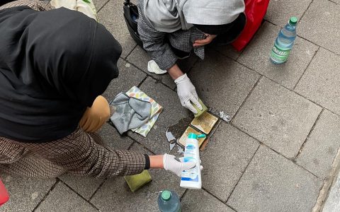 Zwei Frauen reinigen Stolpersteine in Wiesbaden.