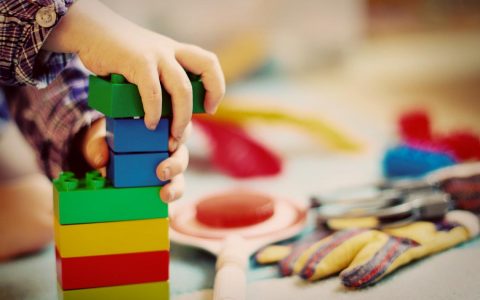 Kind spielt mit Bauklötzen. Alltag in der Kindertagespflege.