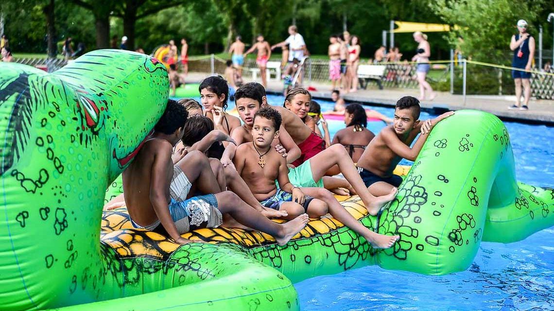 Wasserspieltage: Kinder auf aufblasbaren Spielgeräten im Becken eines Freibads
