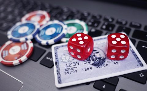 Würfel und Karten liegen auf einem Laptop. Datenschutz, sicheres Spieen im Internet.