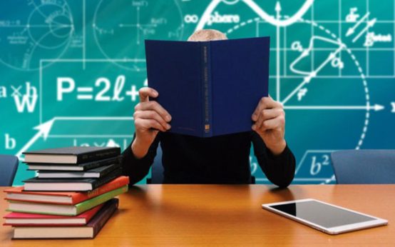 Schüler steckt sein Gesicht in Bücher im Klassenzimmer. Pisa Studie