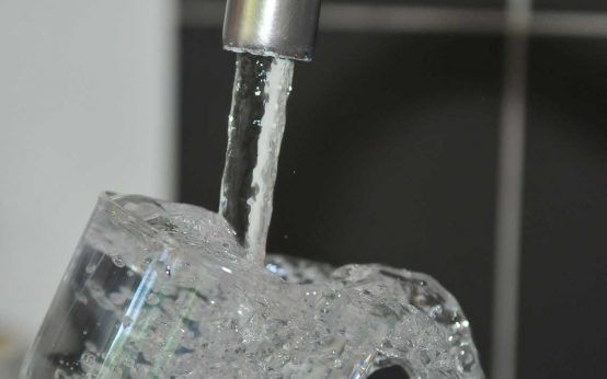 Wasserverbrauchssteuer: Trinkwasser aus Wasserhahn, Glas wird aufgefüllt.
