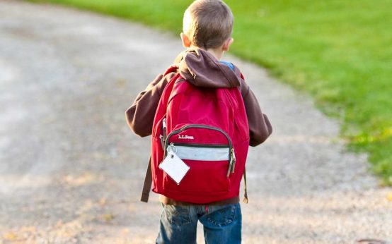Erstklässler, Schulstart, Kleiner Junge mit Schulranzen auf dem Weg zur Schule.