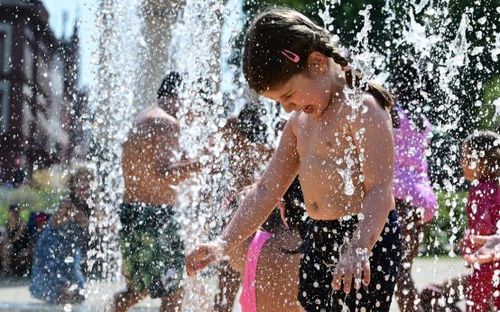 Kleines Mädchen vergnügt sich am Wasserspielplatz mit Wasserspiele.