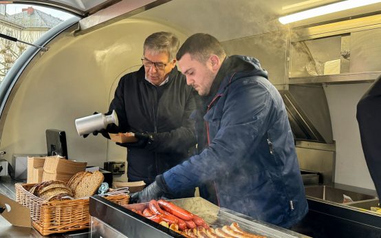 Oberbürgermeister Gert-Uwe Mende (links) verkaufte am Streetfood-Wagen der Wiesbadener Kochwerkstatt Currywurst für einen guten Zweck
